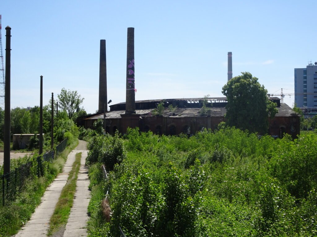 path connecting to abandoned buildings with chimney stacks in leipzig east germany