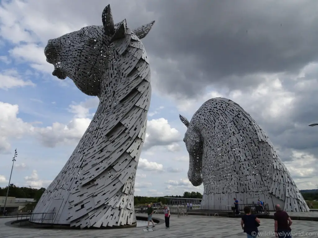 view of the kelpies in falkirk from behind with people looking at the sculptures