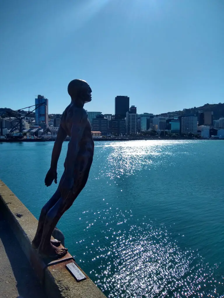 Solace in the Wind statue by Max Patte sculpture of a man leaning on a ledge toward the water on the waterfront wellington