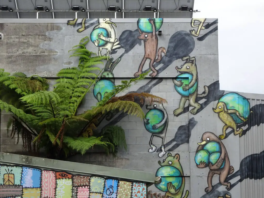 street art showing dogs and birds walking on two legs carrying globes on a wall in new plymouth new zealand