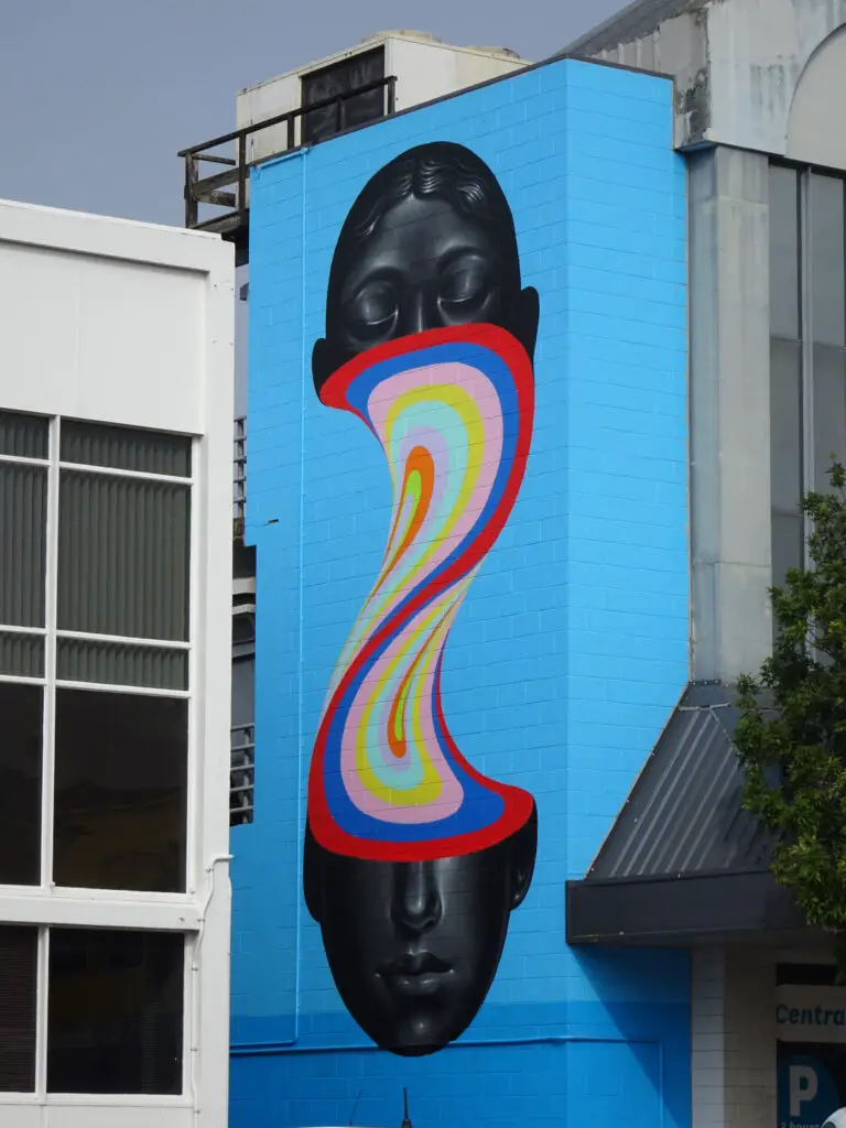 mural of a black head split in two by a curved rainbow by gina kiel in whangarei new zealand