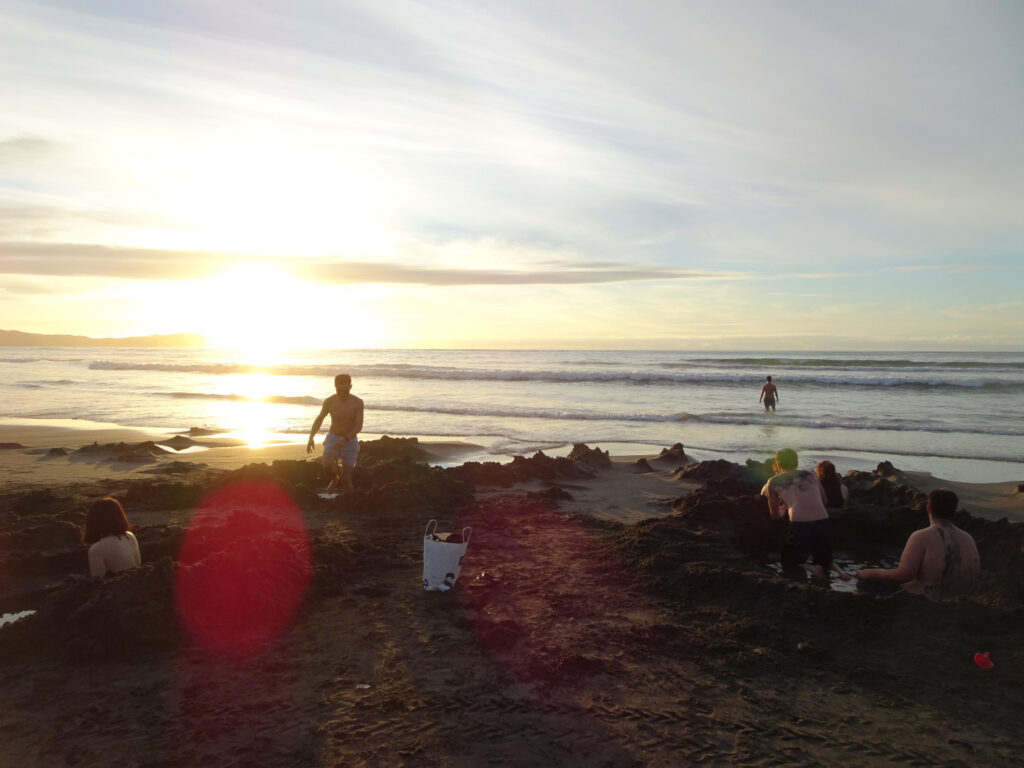 people digging hot pools at kawhia ocean beach- a hot water beach in the north island in new zealand