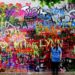 lauren standing in front of the love wall in prague - a colourful wall covered with graffiti - czech republic - wildlovelyworld