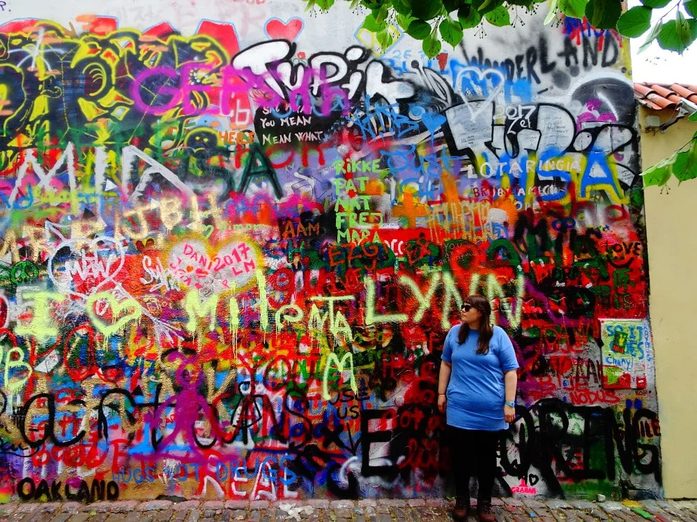 lauren standing in front of the love wall in prague - a colourful wall covered with graffiti - czech republic - wildlovelyworld