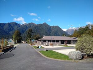 sunny day with blue sky and clearly visible green mountains at fox glacier top 10 holiday park new zealand