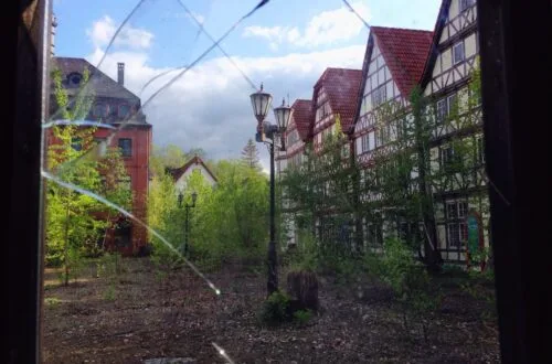 german style buildings in abandoned japanese theme park through broken window