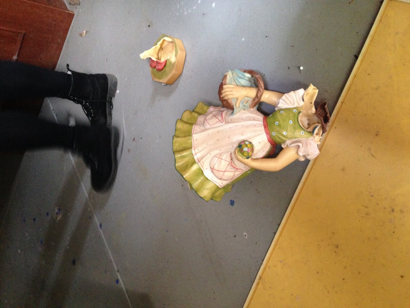 broken ceramic doll without head lying on the floor