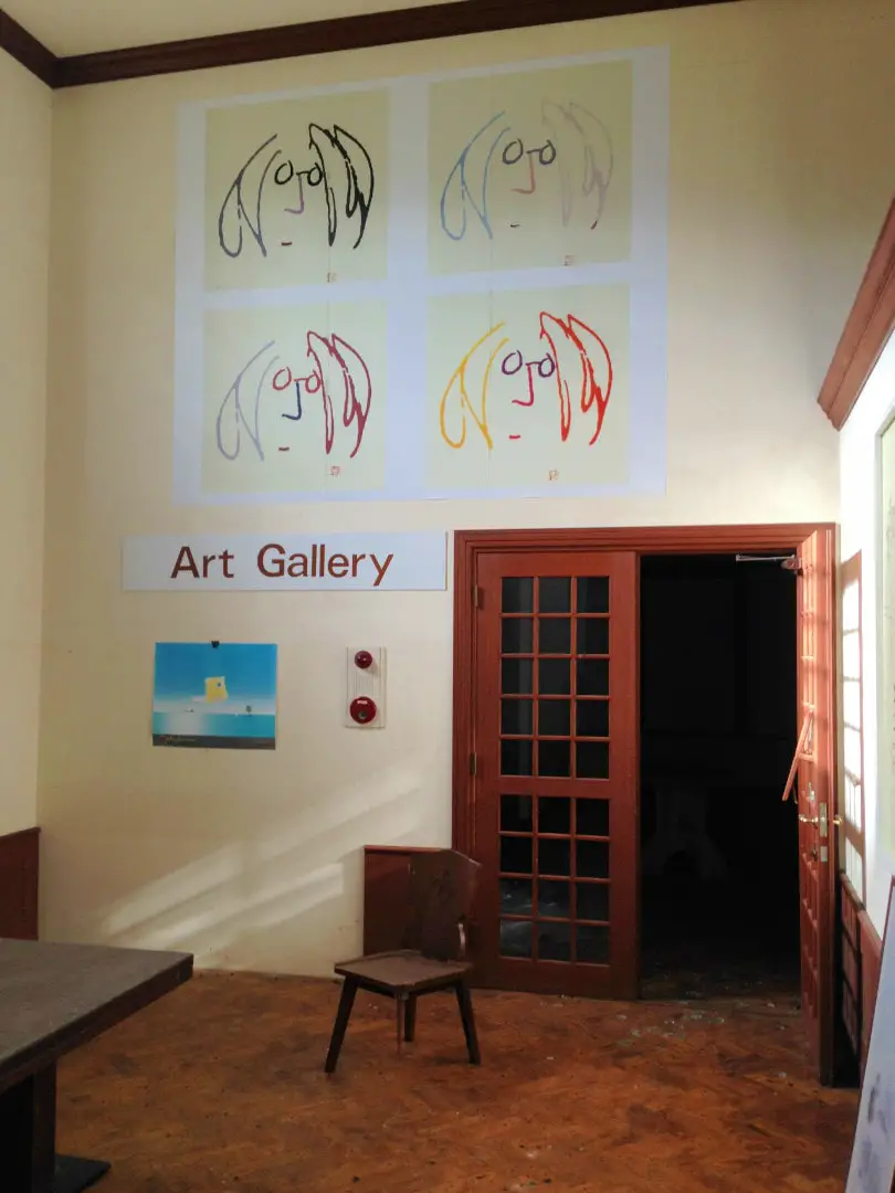 inside the john lennon art gallery cafe at the gluck kingdom with drawings of john lennons face on the wall and an open doorway with a chair