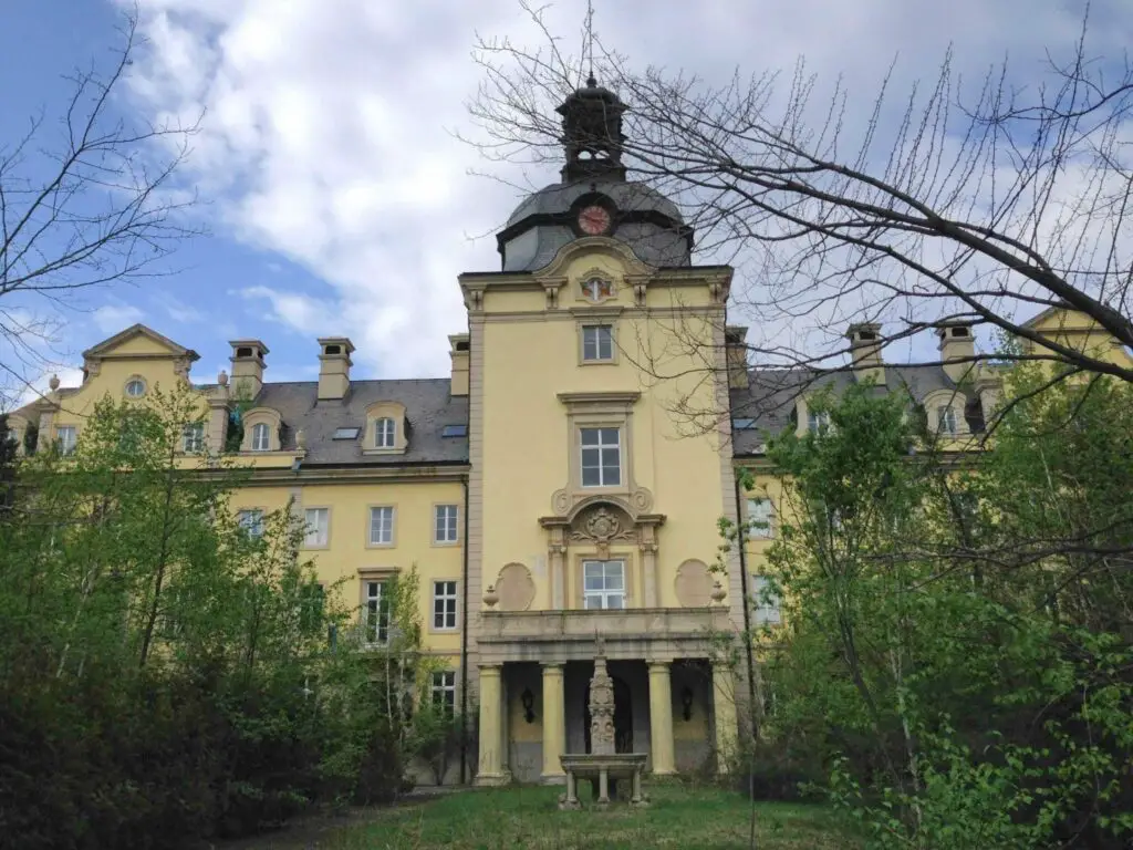 large yellow building with columns, clock and bell tower at the gluck kingdom - abandoned german theme park in hokkaido japan - recreation of the Bückeburg Palace 