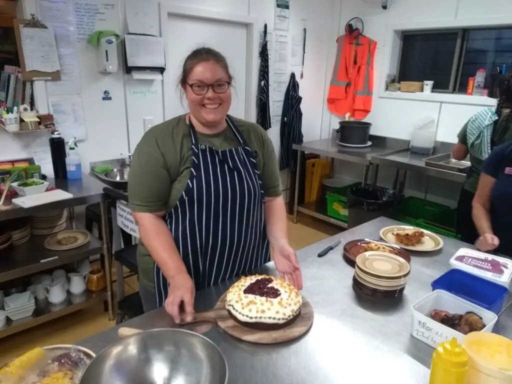 lauren decorating a carrot cake with a heart in a kitchen at a lodge in the north island