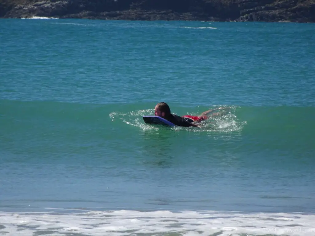 fiachra smiling and enjoying riding a body board in new zealand at curio bay