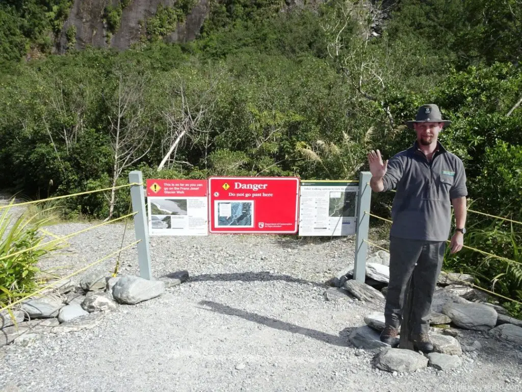 franz josef glacier trail closed with danger - do not go past here - signs and a realistic cardboard cutout of a DOC ranger dressed in uniform holding his hand up indicating 'stop'