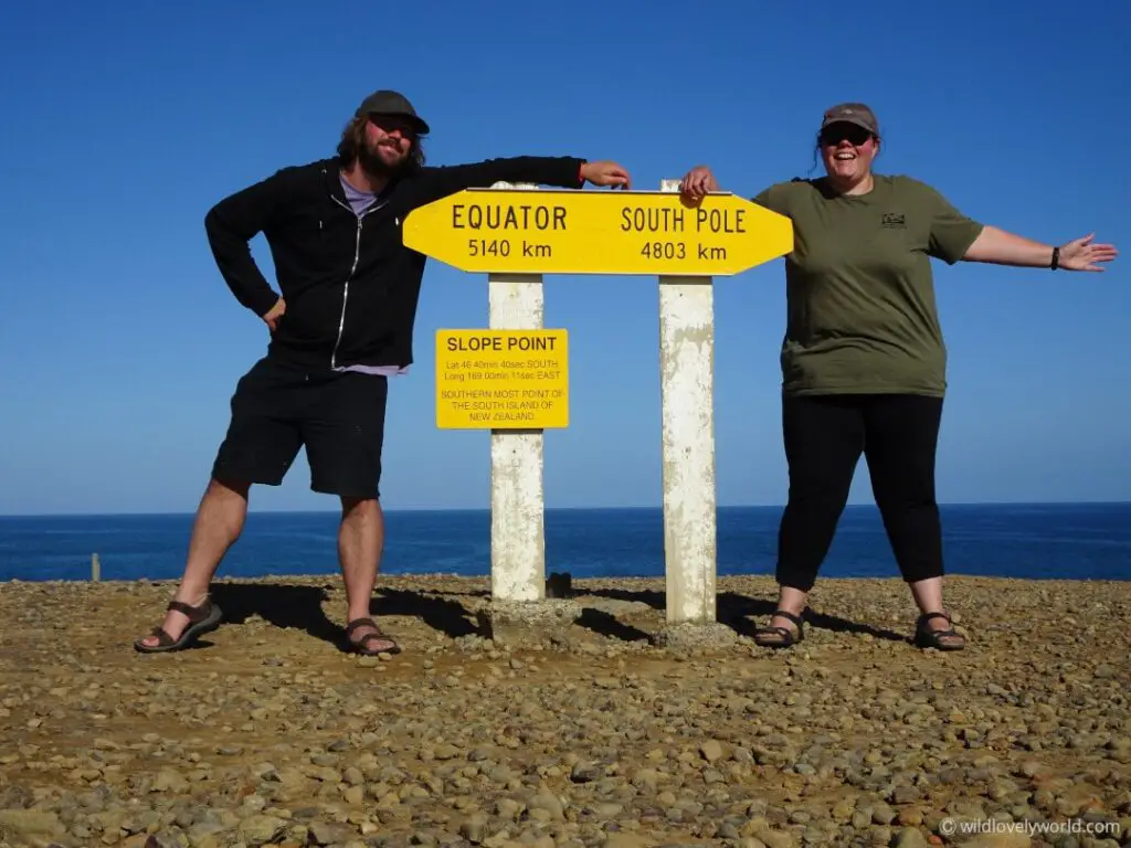 lauren and fiachra standing at the slope point sign, showing the distance to the equator 5140 km and the south pole 4803 km