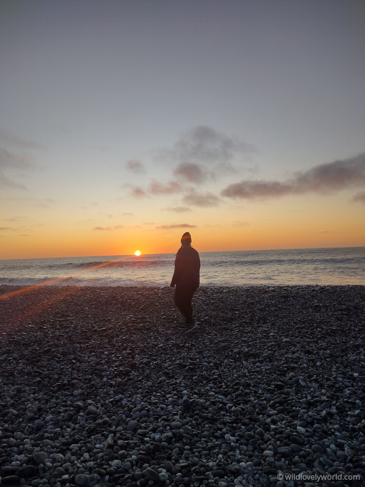 lauren, a woman, on gillespies beach at sunset, new zealand west coast