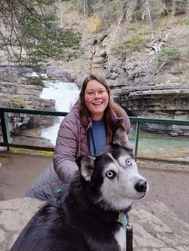 lauren smiling with a husky and a waterfall behind them both
