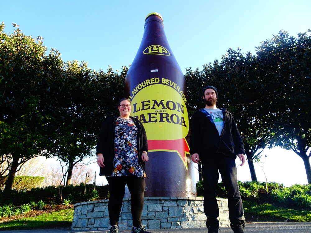 lauren and fiachra standing in front of the lemon and paeroa big bottle north island new zealand