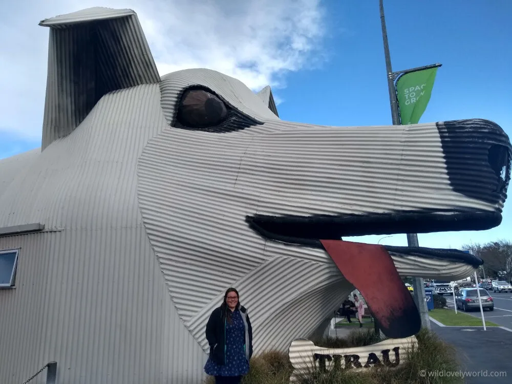lauren standing in front of the tirau i-site building made from corrugated iron and shaped like a white dog with red tongue sticking out