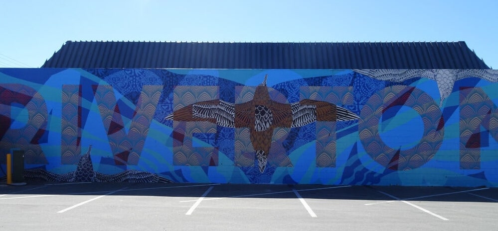 mural on side of building that says riverton in blue and has a brown bird flying in the middle