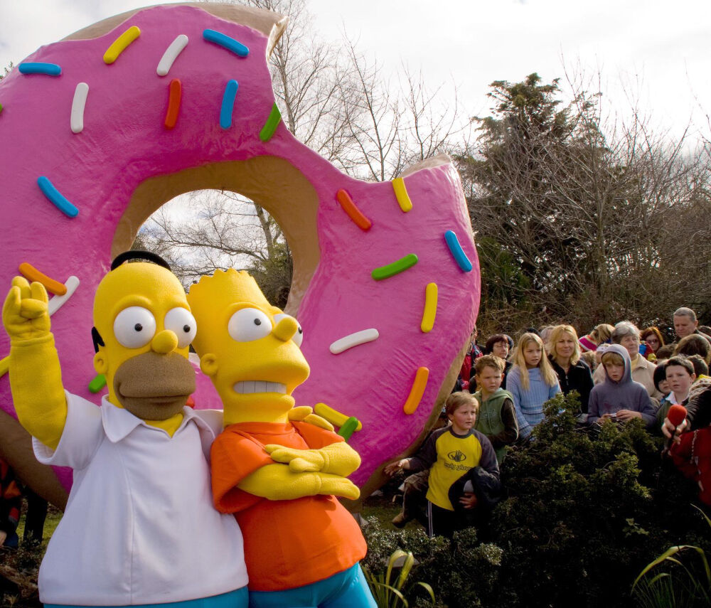 homer simpson and bart simpson and a group of children standing with the giant springfield doughnut new zealand