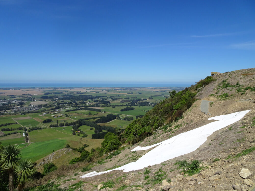 waimate white horse monument view from the top of the hill showing fields and sea in distance under a blue sky