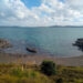 small cove beach with clear blue water, blue cloudy sky, along matiatia coastal walk on waiheke island auckland new zealand