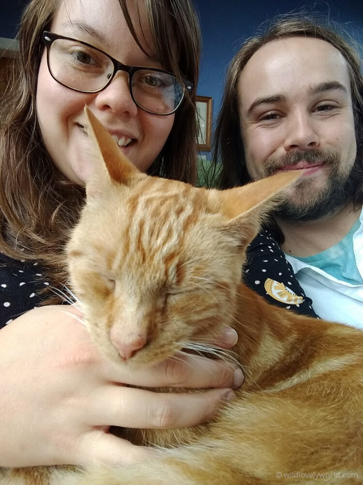 lauren and fiachra smiling at the camera and holding a ginger cat