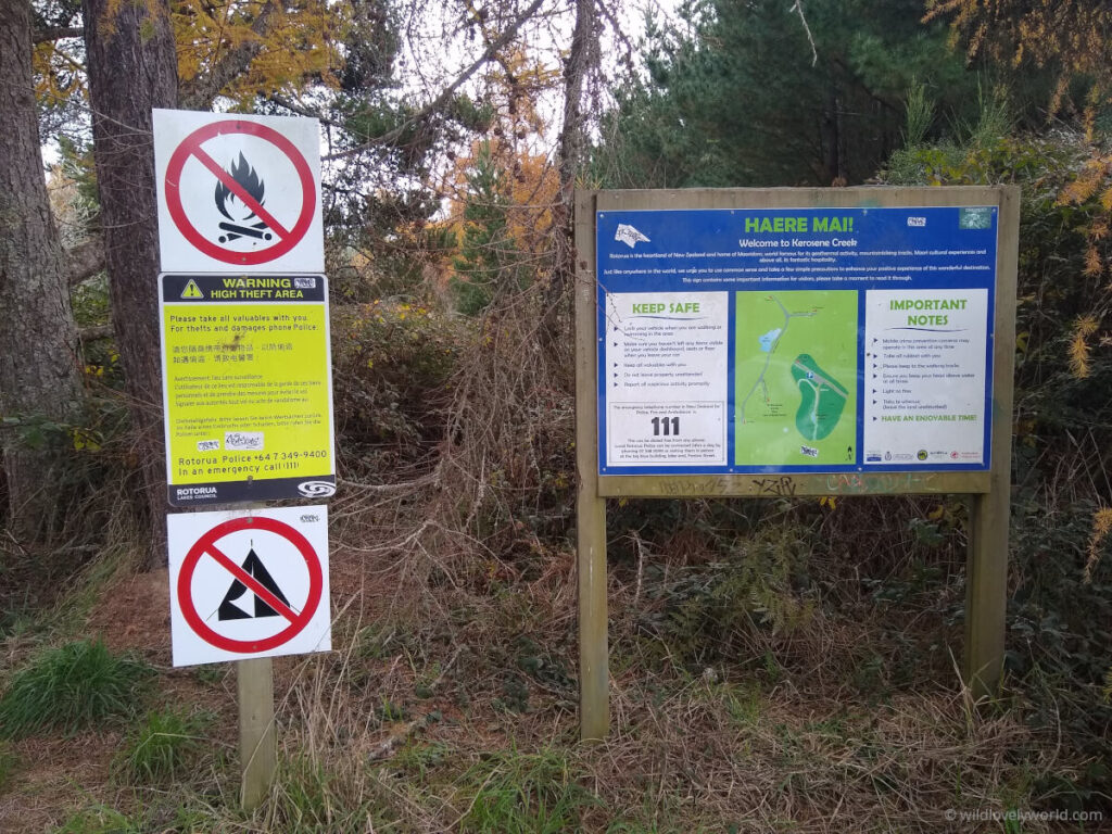 warning and information signs at the entrance to kerosene creek, a natural hot geothermal river in new zealand, near rorotura. the signs say no fire, camping, warn of high thefts, provide a map on the area and how to keep safe