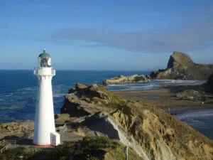 view of castle point lighthouse, beach, and castle rock, at the castlepoint scenic reserve, in wairarapa, north island, new zealand