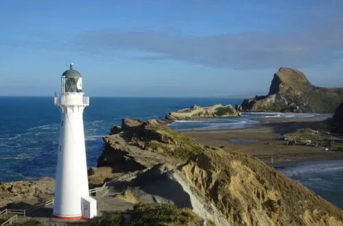 view of castle point lighthouse, beach, and castle rock, at the castlepoint scenic reserve, in wairarapa, north island, new zealand