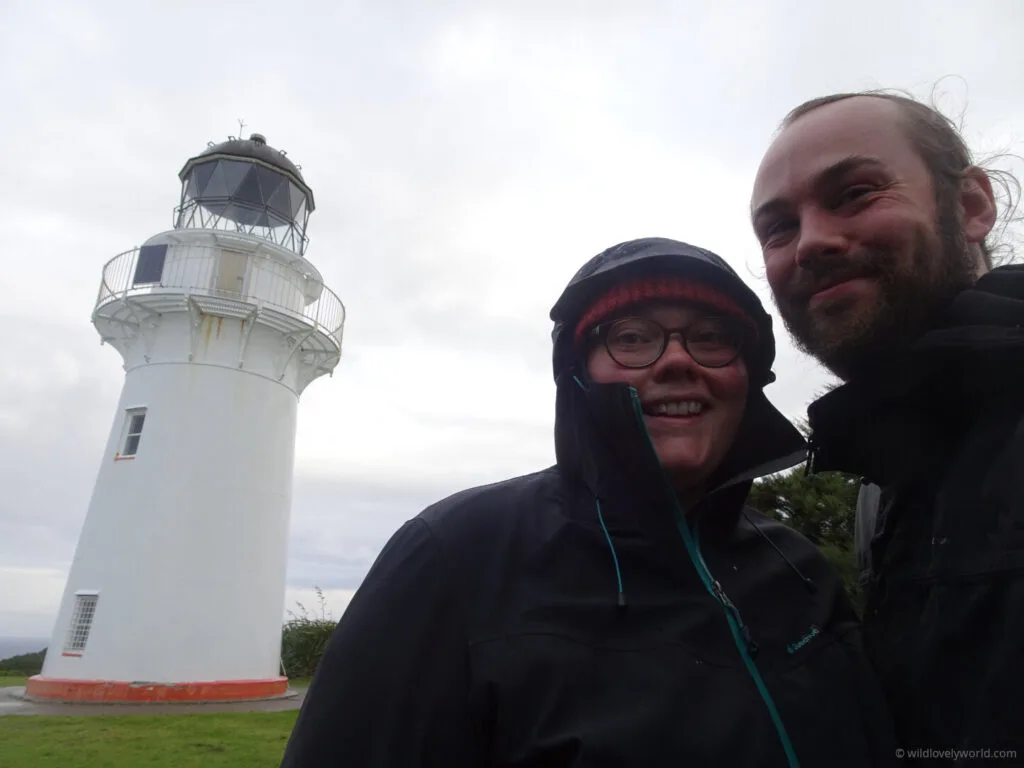 lauren and fiachra smiling at the camera in a selfie at east cape lighthouse in new zealand
