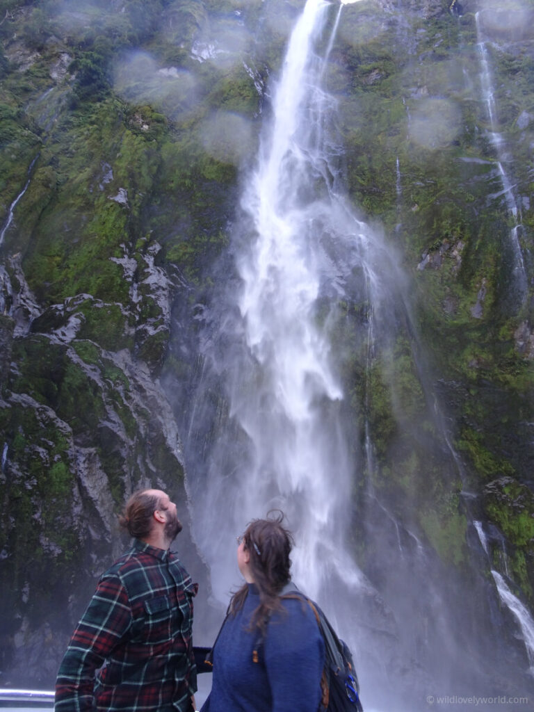 lauren and fiachra looking up at stirling falls in milford sound in new zealand