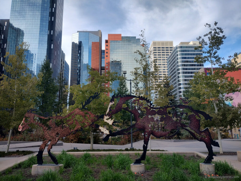 horse sculptures in calgary downtown with tall buildings and trees