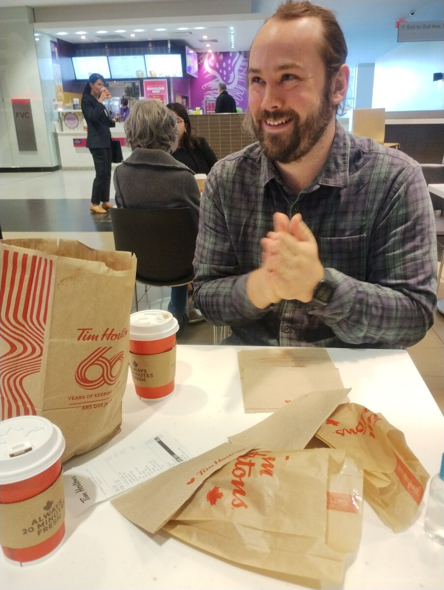 fiachra smiling with tim hortons bags and coffee cups