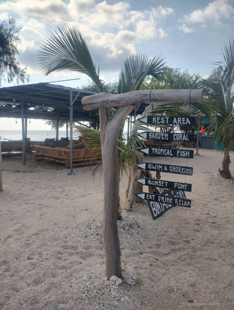 signpost on gili meno island directing to snorkelling spots such as coral garden, tropical fish, swim and snorkelling, sunset point, on the west side of the island