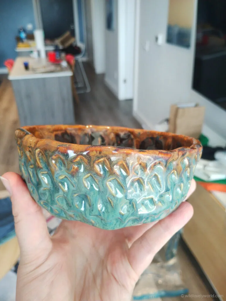 hand holding a ceramic bowl with blue and brown glazes