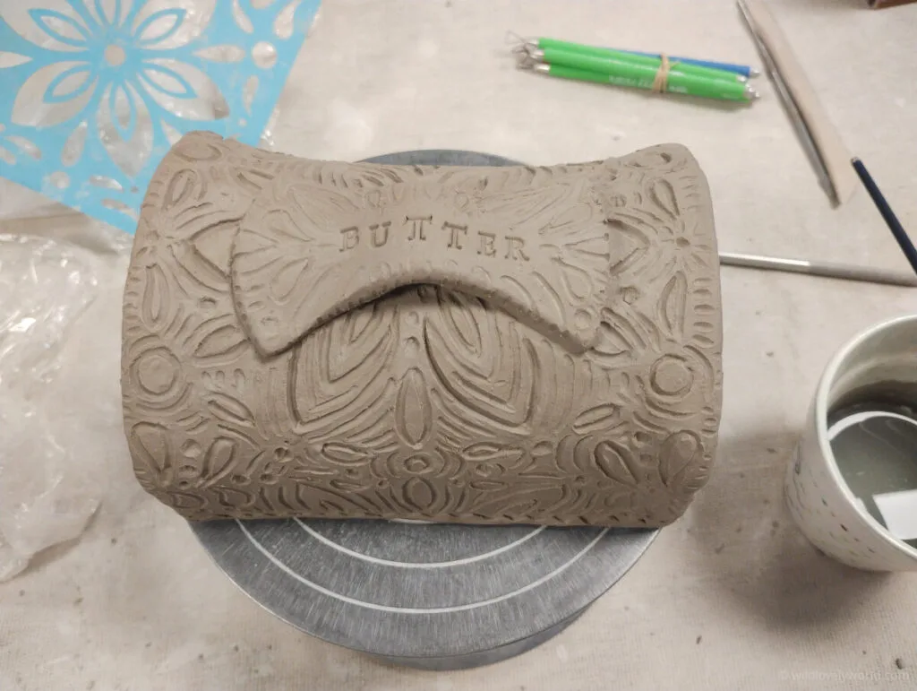 a carved butter dish lid made of clay
