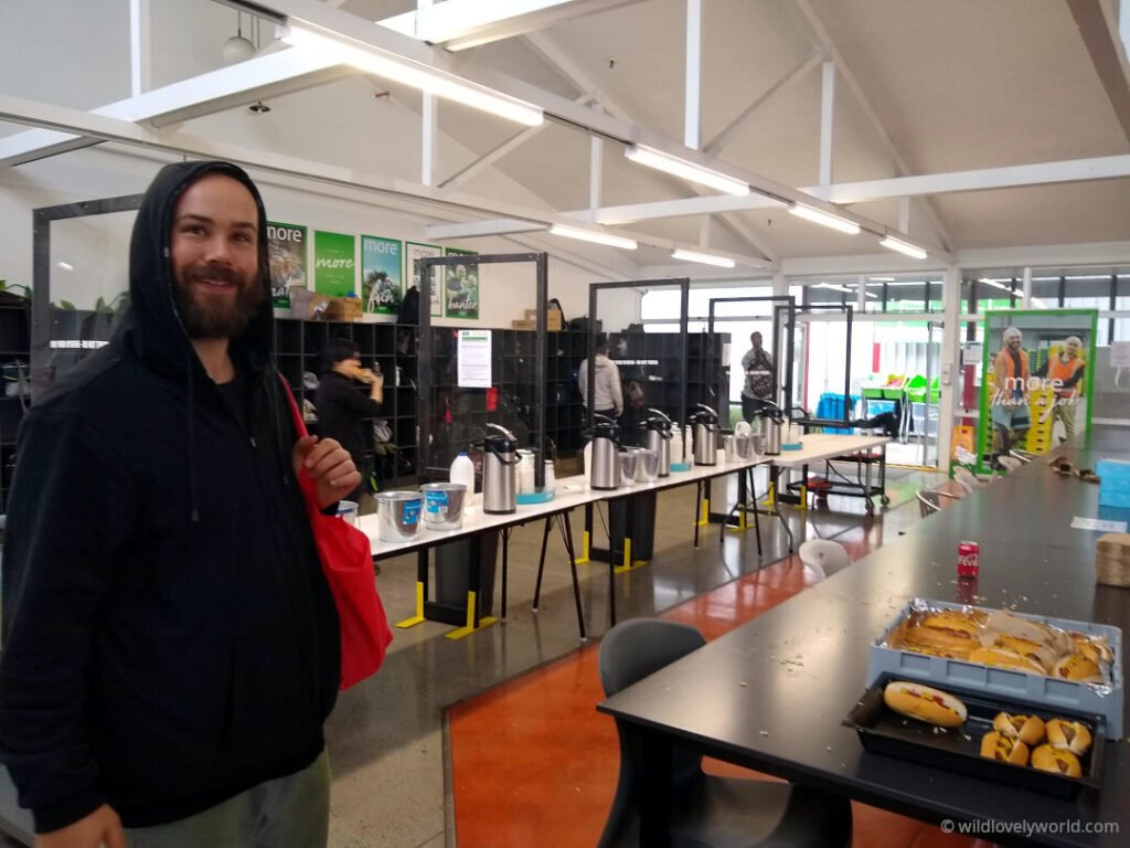 fiachra in the interior of the kiwifruit packhouse cafeteria, showing tea and coffee area and free hot dogs, and bag storage