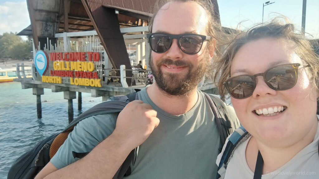 fiachra and lauren selfie with the welcome to gili meno lombok sign at the harbour