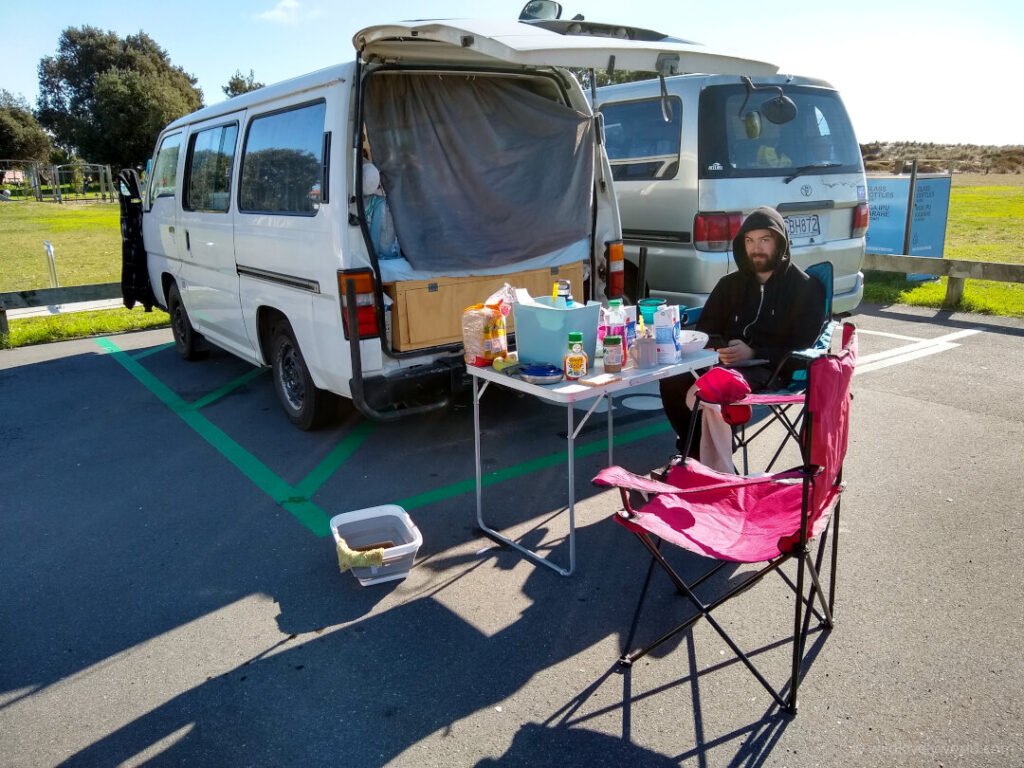 fiachra sitting outside our campervan at freedom camping near papamoa beach