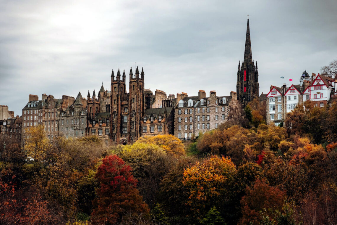 autumn in edinburgh - view of edinburgh old town buildings fronted by trees with autumnal colors